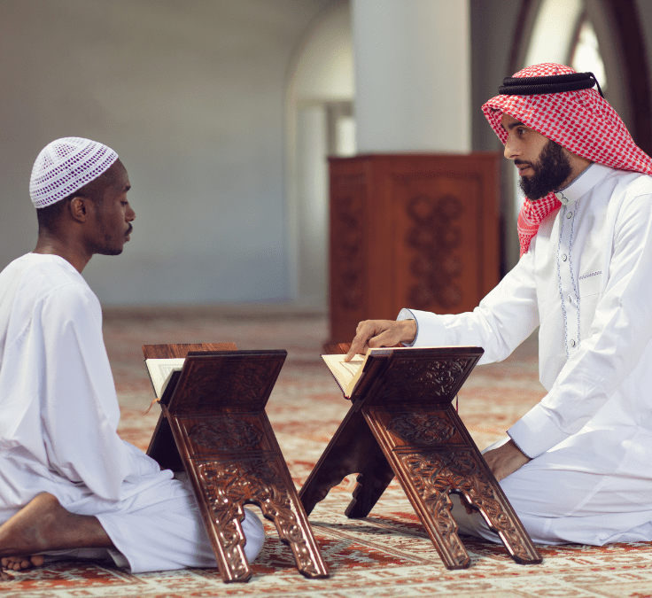 Dos hombres en una mezquita, uno levantando el dedo índice realizando la Shahada