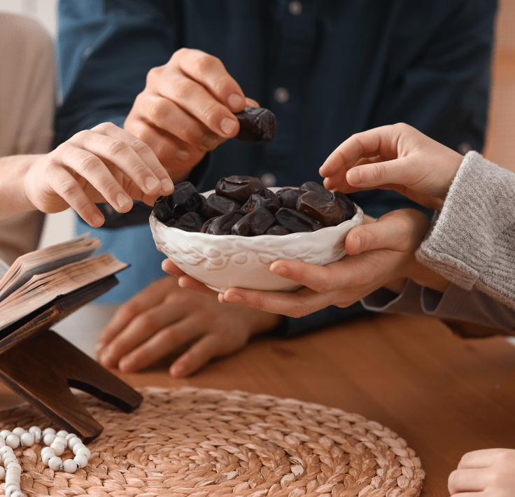 Plato con dátiles y manos tomándolos para romper el ayuno en Ramadán