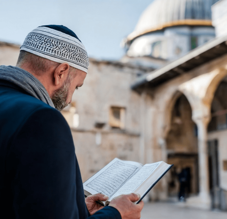 Hombre musulmán leyendo el Qurán con una mezquita al fondo durante el amanecer o anochecer