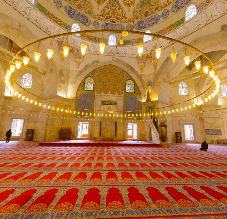 Interior de una mezquita con gran lámpara y alfombra roja representando unidad espiritual