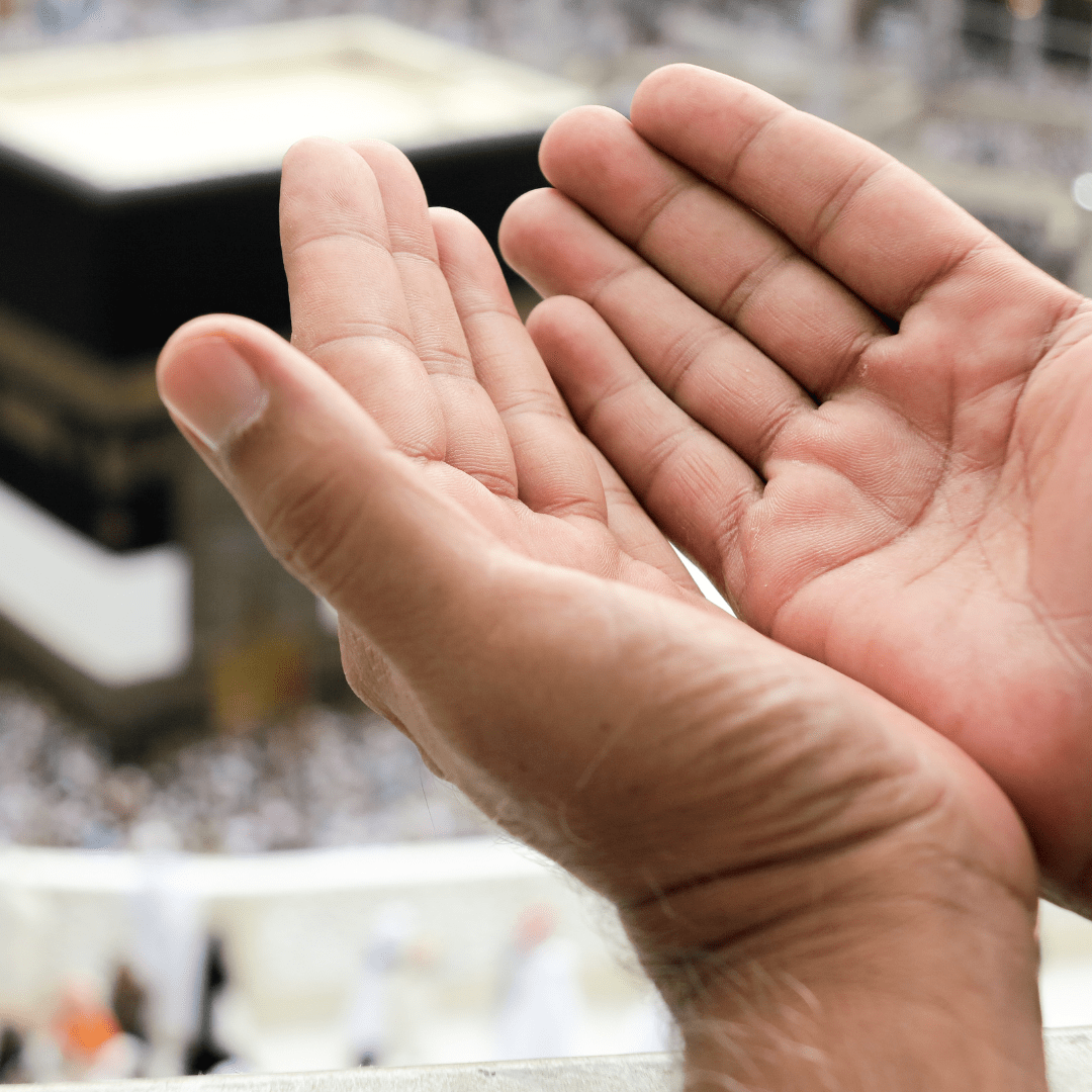 Manos levantadas en súplica con la Kaaba de fondo en La Meca